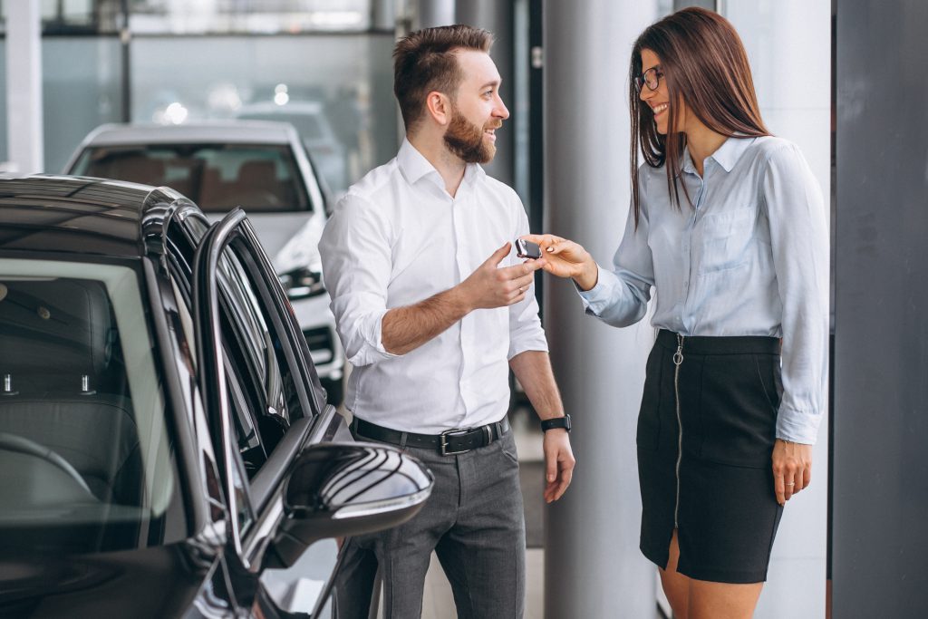 leasing samochodu, kobieta przekazuje kluczyki do auta mężczyźnie 